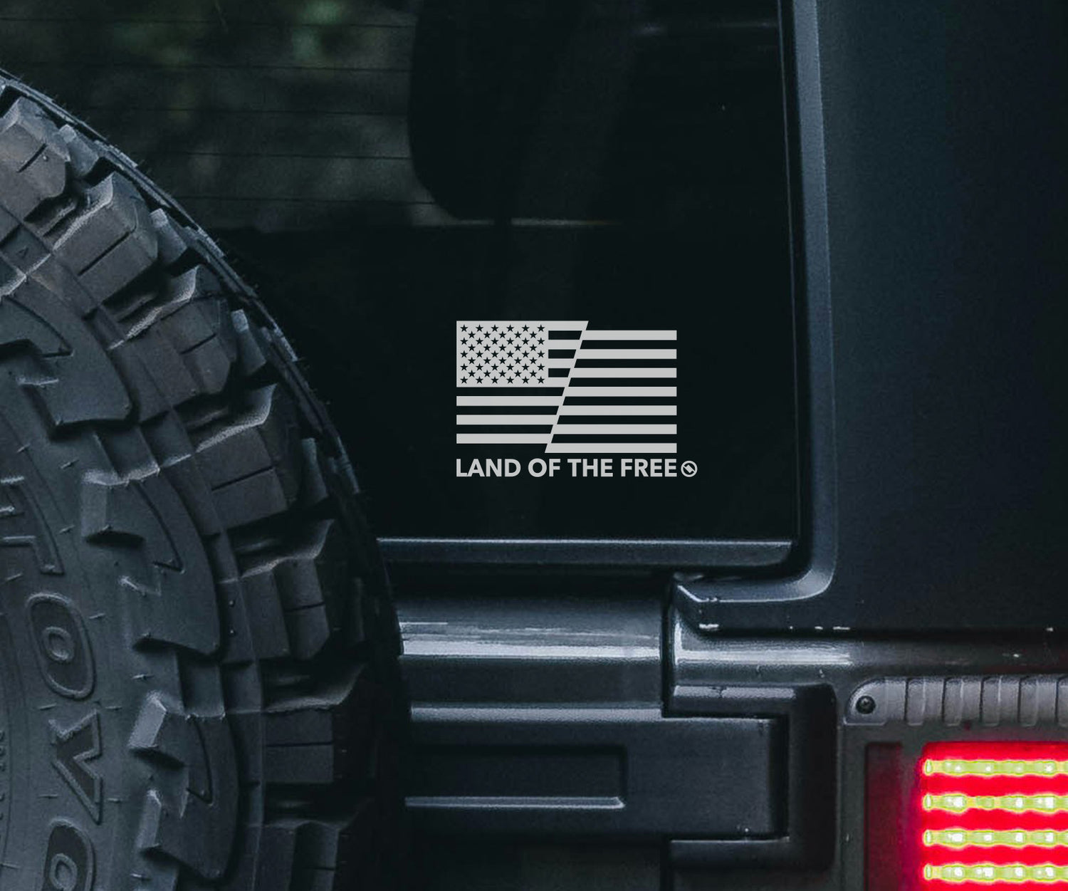 American Flag vinyl decal with "Land of the Free" text on the back window of a Jeep.
